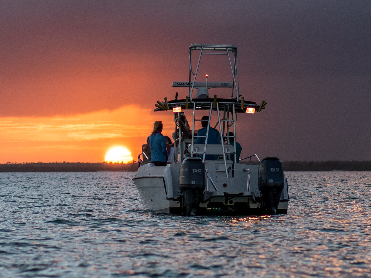 Guests enjoy a boat ride on calm sunset waters near Caerula Mar Club, luxury beach resort on South Andros Island, Bahamas.